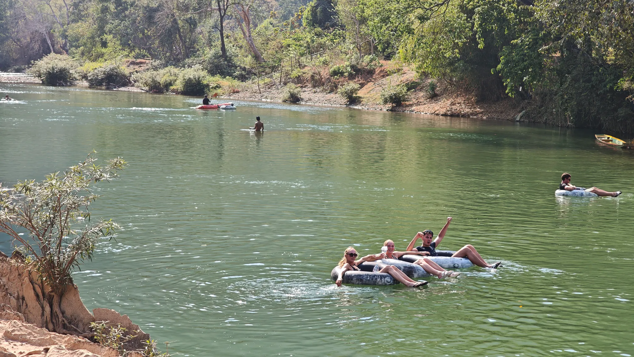 Tubers floating down the Nam Song River on inflatable tubes among packrafters in Vang Vieng