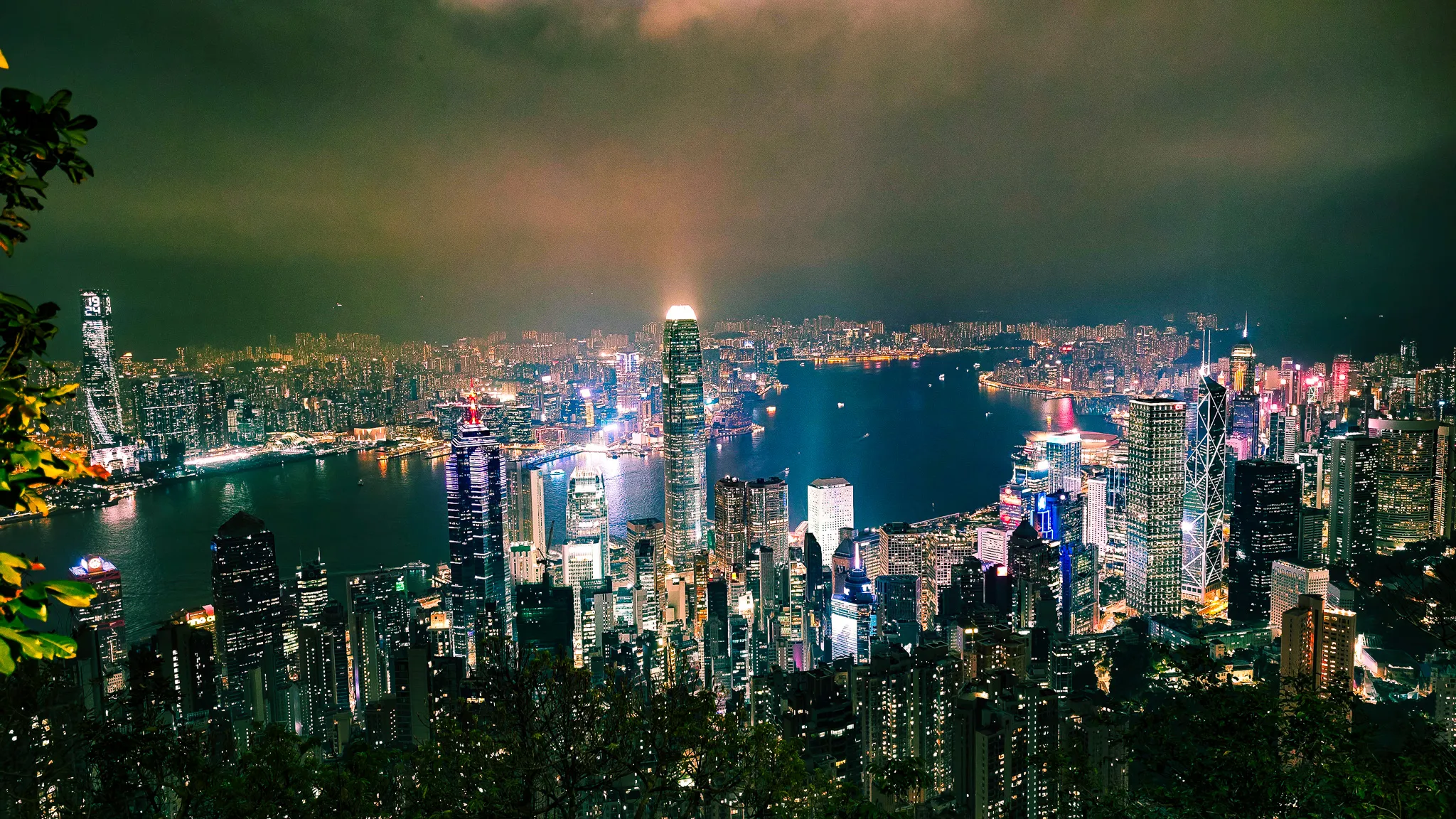 Hong Kong skyline from Victoria Peak at night with dramatic lit clouds and the full harbour panorama