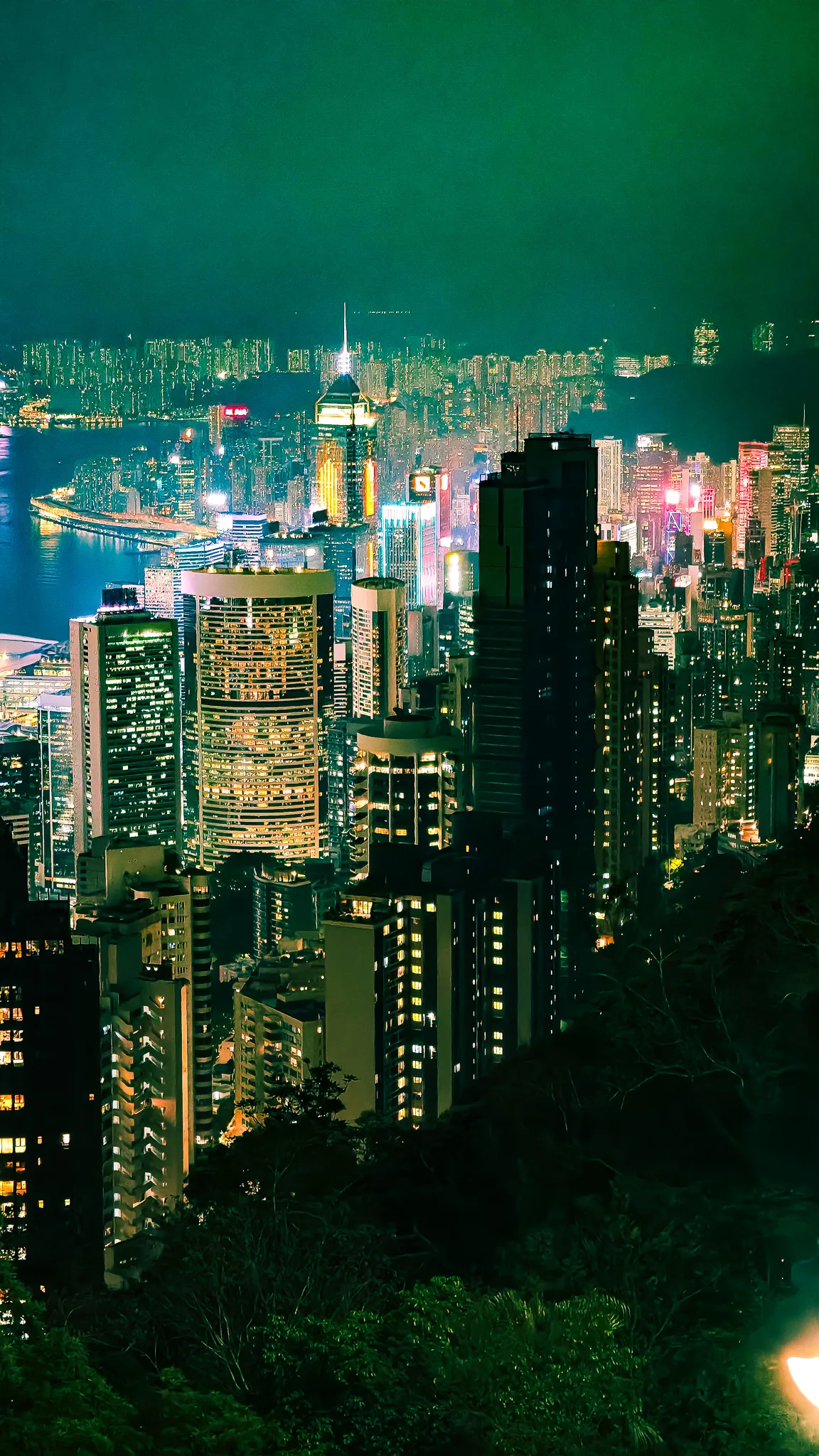 Hong Kong skyline at night viewed from Victoria Peak in portrait orientation with illuminated skyscrapers and Victoria Harbour