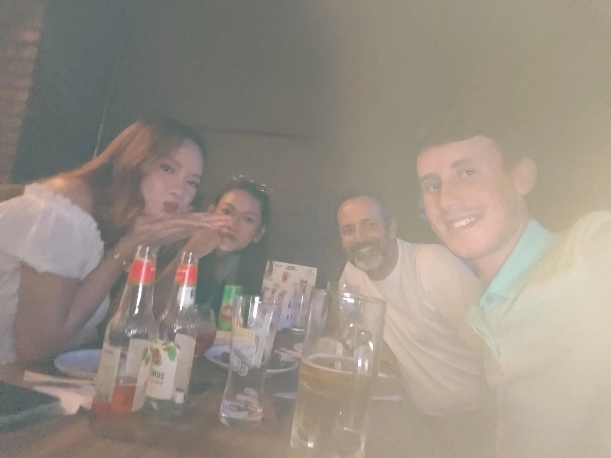 Friends Jenny and Chompoo blowing a kiss during dinner with beers at a Vientiane restaurant