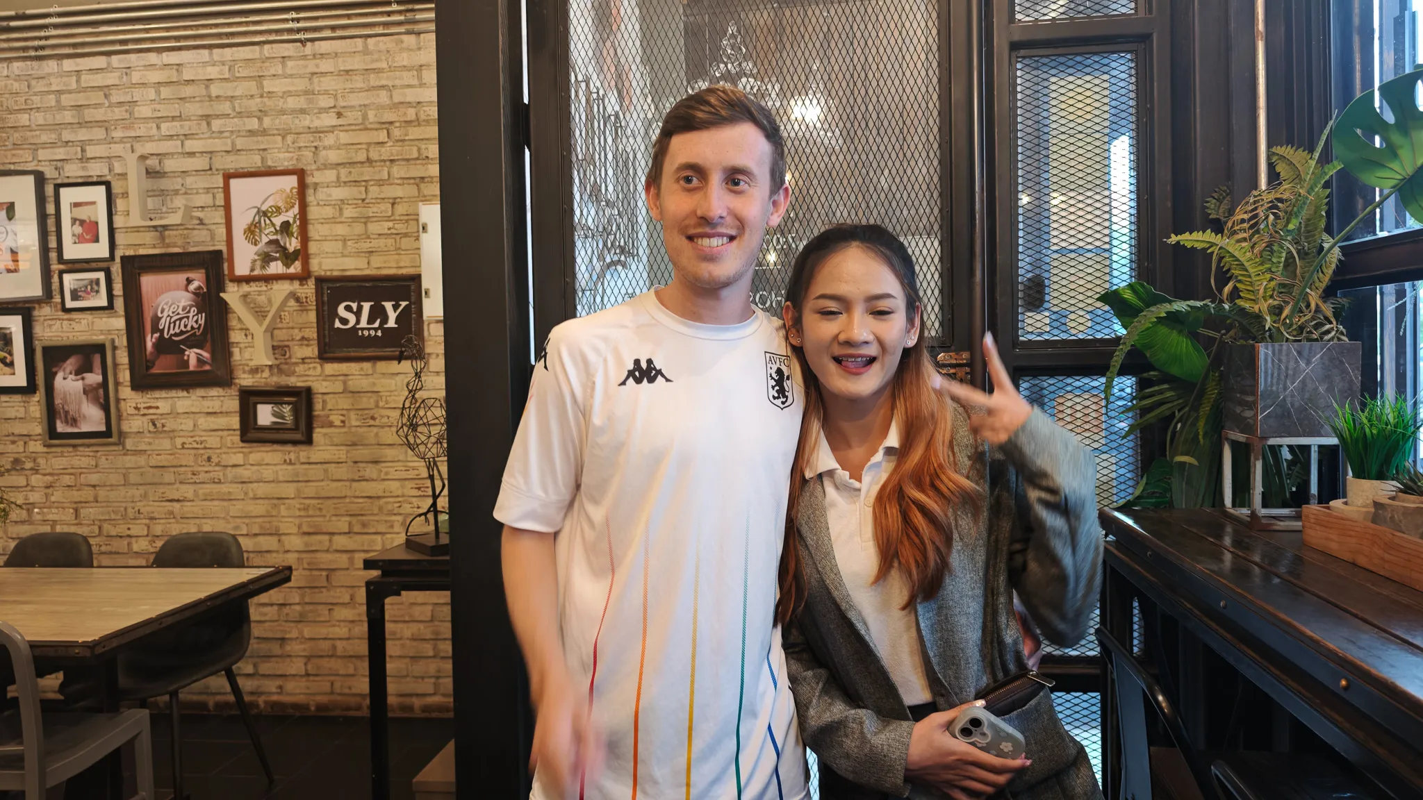 Close-up goodbye photo with a smiling Lao friend giving a peace sign at a Vientiane cafe