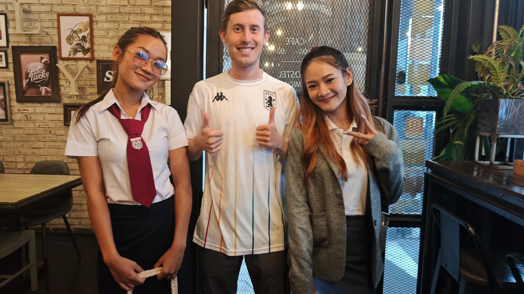 Goodbye photo with two Lao friends at a cafe in Vientiane giving thumbs up and peace signs