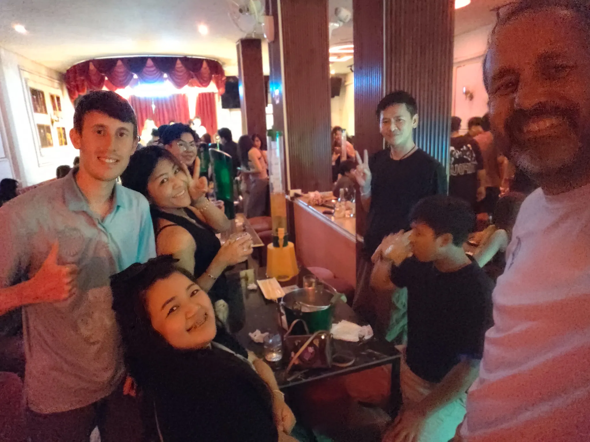 Group selfie with friends including Jenny and Chompoo at a bar in Vientiane with drinks on the table