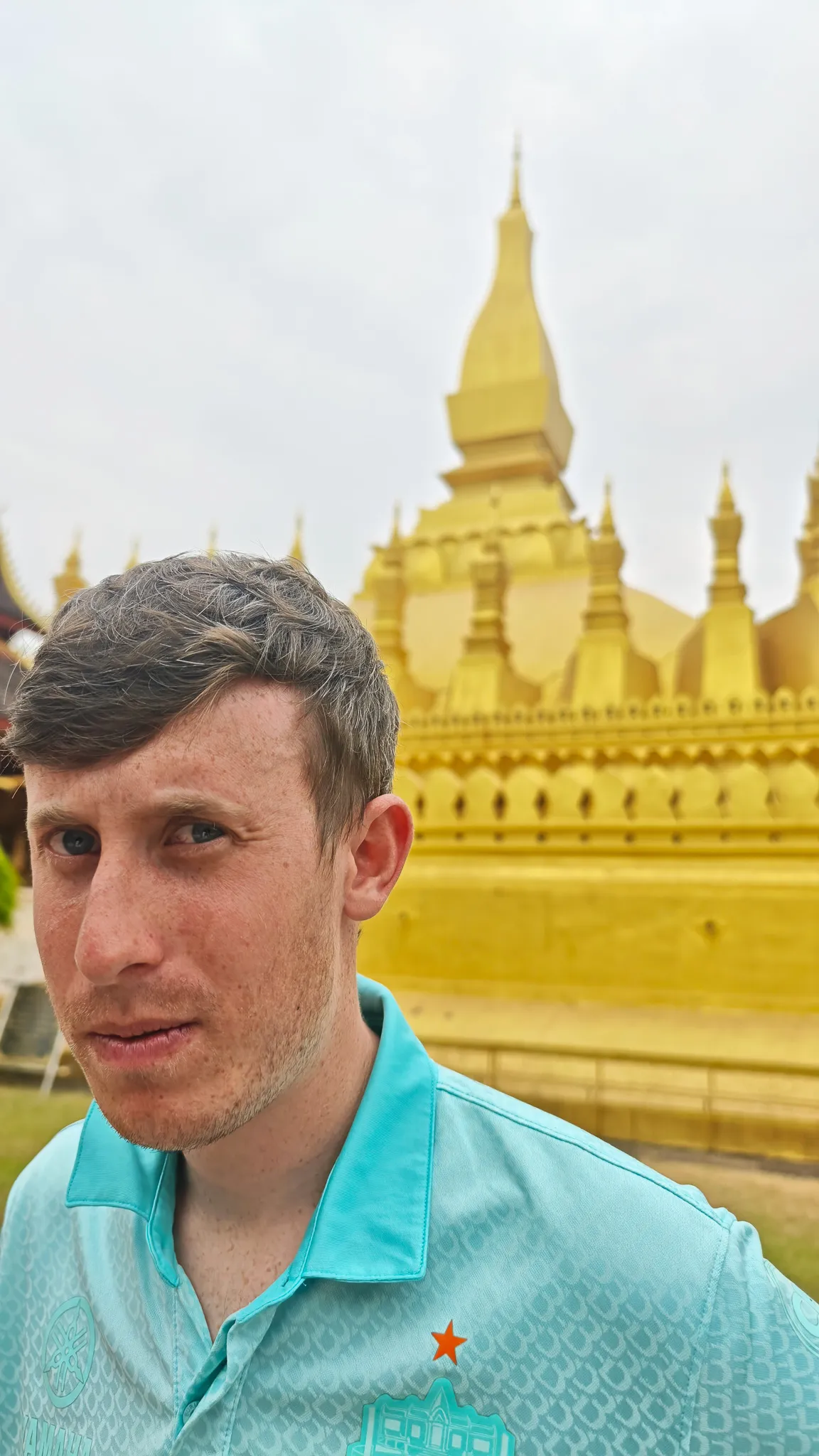 Selfie in front of the golden Pha That Luang stupa in Vientiane wearing a mint green Chang beer football shirt