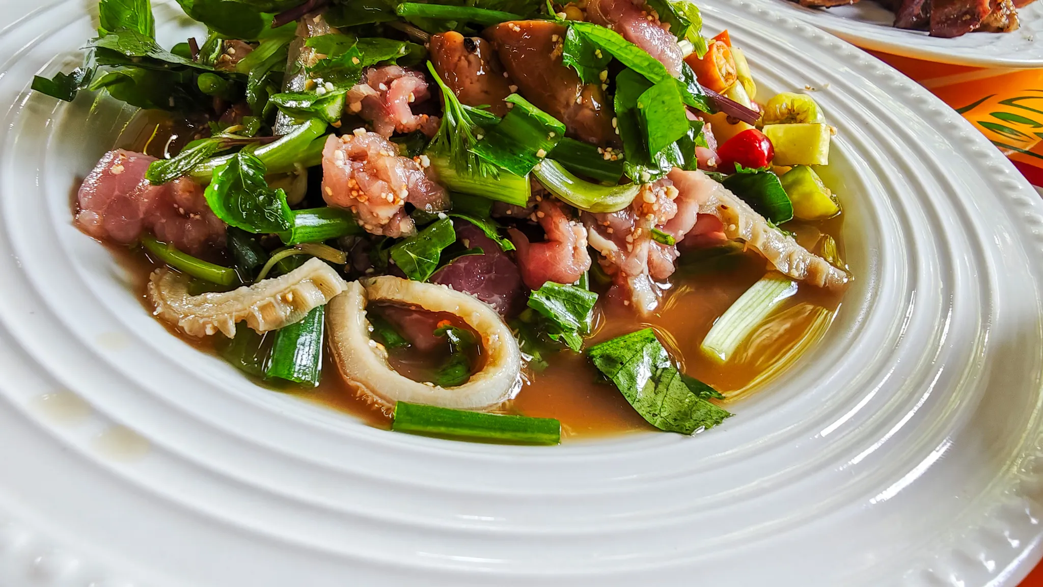 Plate of raw laab with bile, fresh herbs and chillies at Mark Wiens favourite restaurant in Vientiane