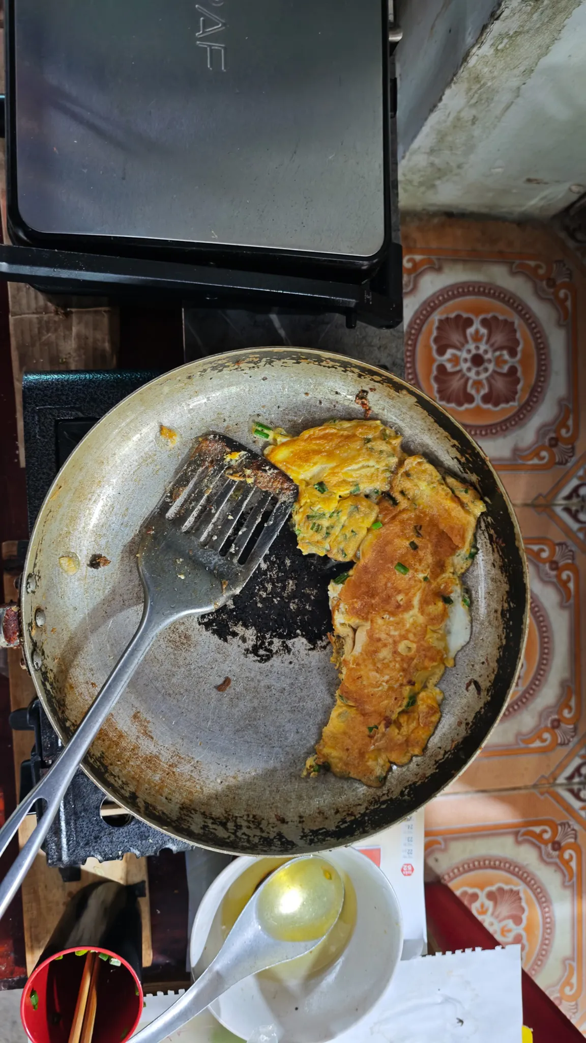 Vietnamese-style omelette with spring onions frying in a pan at a Dien Bien Phu breakfast stall