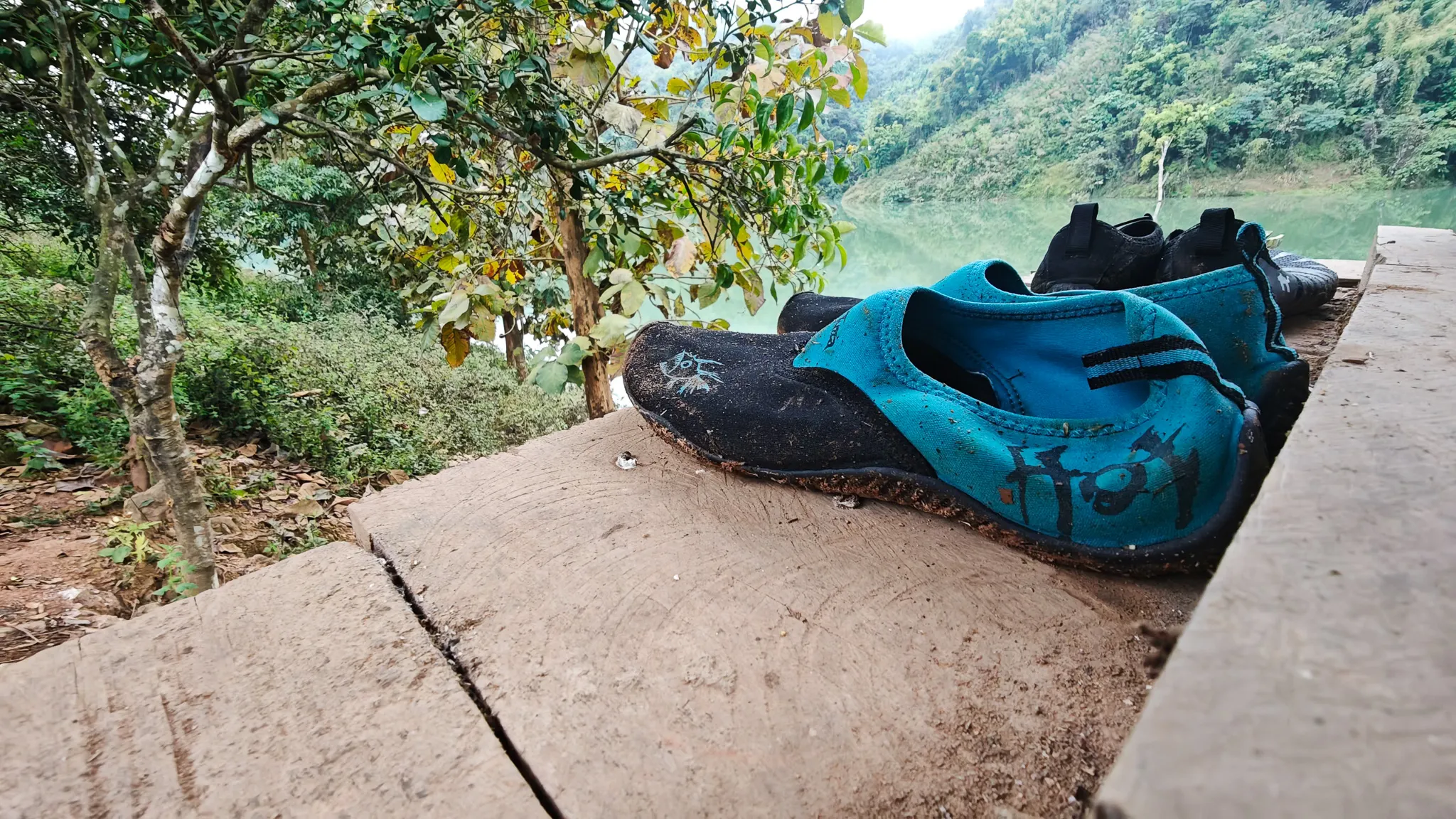 Water shoes drying on a concrete ledge overlooking the green waters of the Nam Ou river in Laos