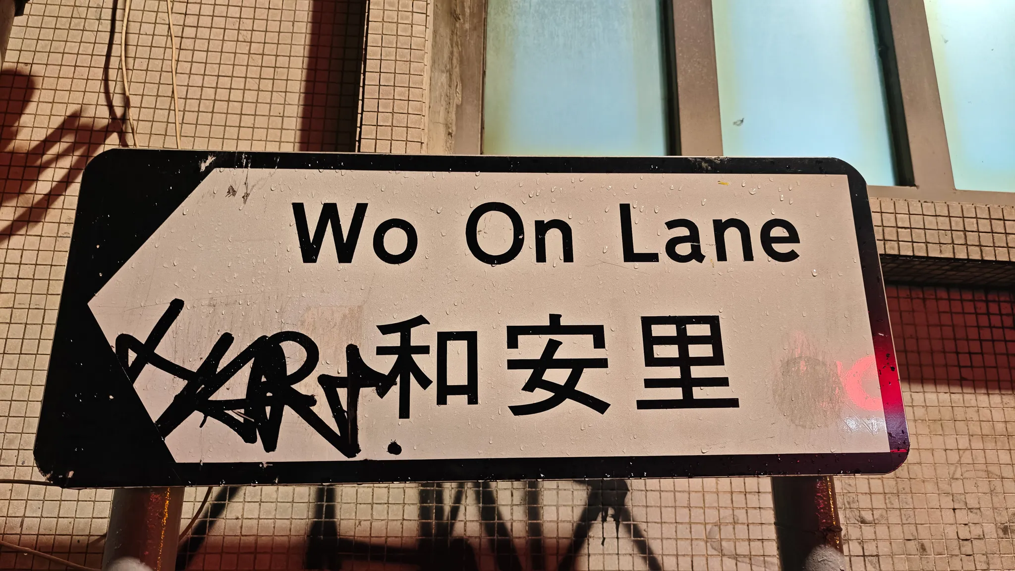 Bilingual Wo On Lane street sign in English and Chinese characters with graffiti in Hong Kong
