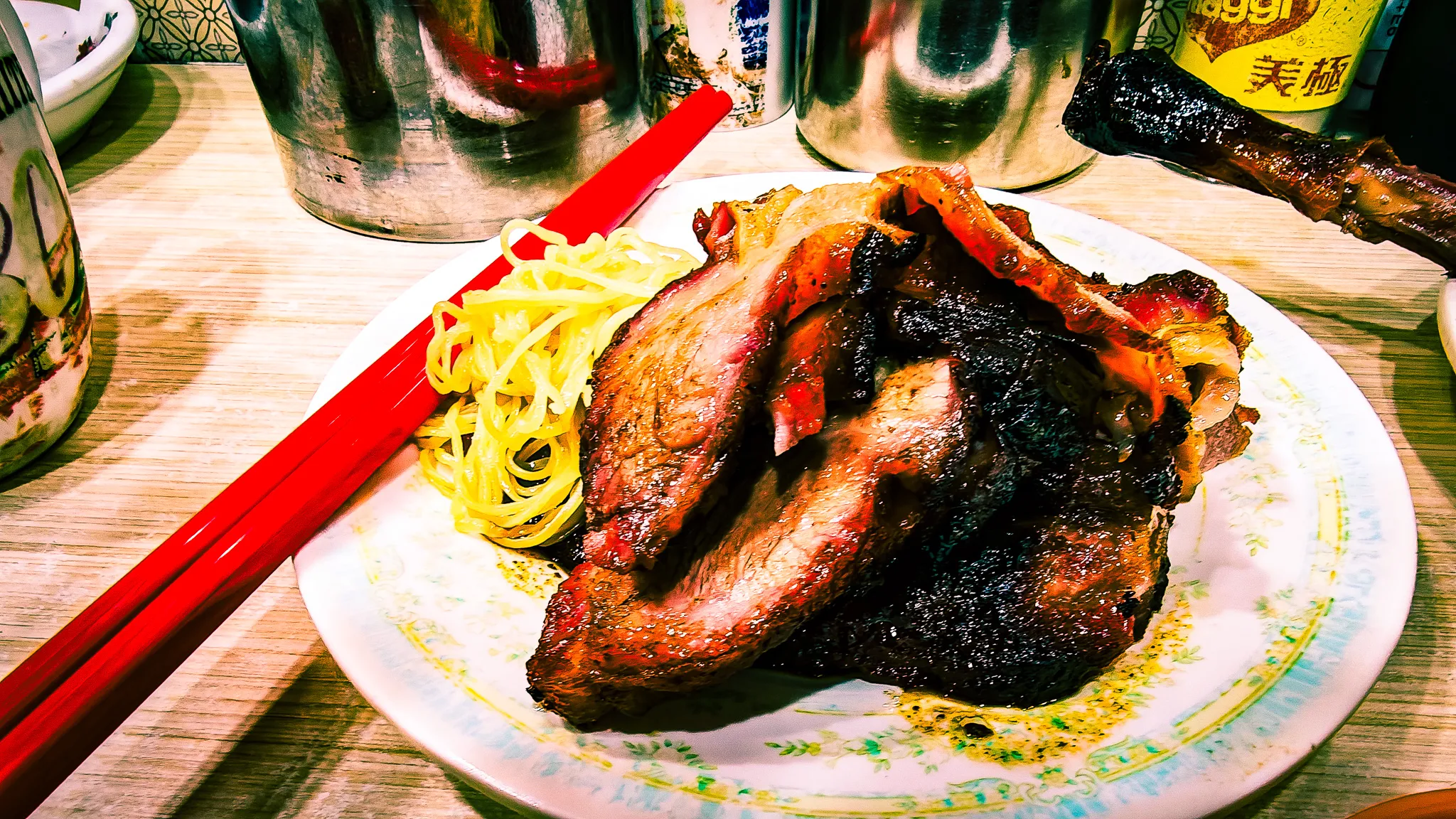 Plate of roast goose leg with noodles and red chopsticks at Yat Lok restaurant in Hong Kong